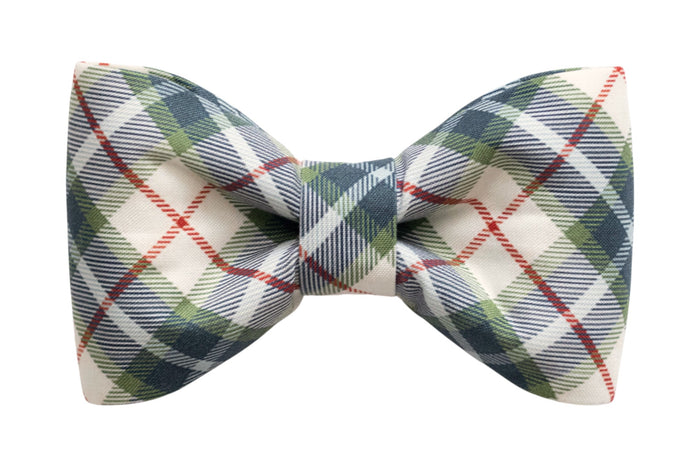 Classic fabric bow tie in classic holiday hues in a tartan plaid pattern, accented by thin diagonal stripes. The bow tie is neatly structured with crisp edges and a central knot band in matching plaid fabric.