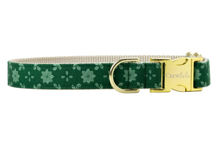 Floral dog collar crafted from green fabric with a light green symmetrical flower and dot pattern. The collar is constructed with a nylon woven backing and includes sleek  hardware: a branded buckle with “Crewlala” text and a matching D-ring for attaching accessories.