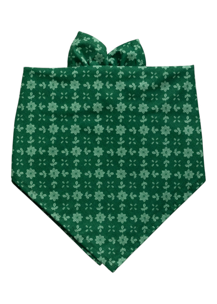 Dog bandana made from deep green fabric patterned with evenly spaced light green floral motifs. The floral design consists of daisy-like blooms arranged in neat vertical and horizontal rows.