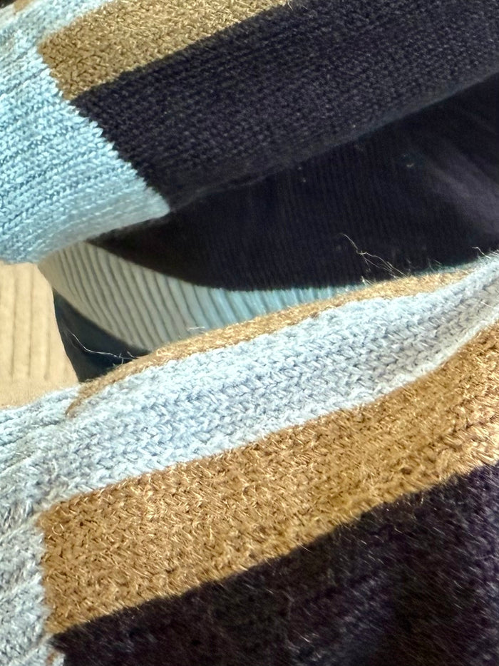 Multicolor knit stripes on sweater sleeve cuff in light blue, navy, and tan