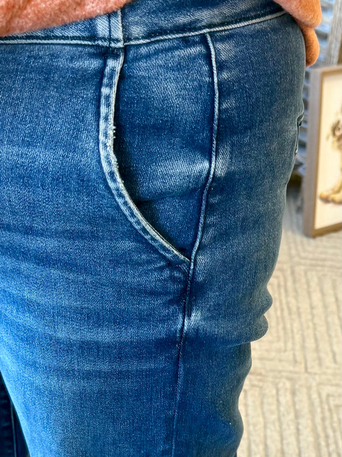 Medium-wash denim jeans close-up, back yoke seam and right back pocket