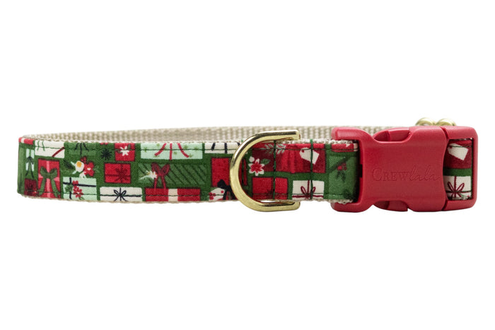 Holiday dog collar made from fabric featuring a tightly packed grid of gift boxes, each wrapped with decorative bows and tags in festive colors. The collar is backed with nylon webbing and finished with a branded “Crewlala” side-release buckle and D-ring.