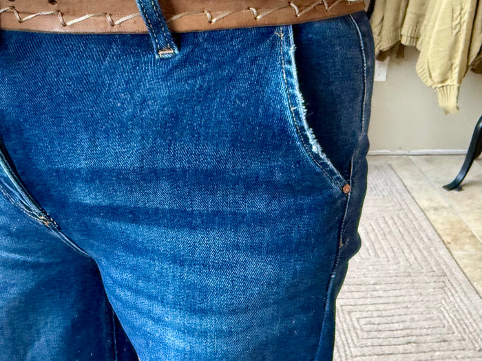 Blue wash denim jeans with slanted front pocket opening and angled seam at thigh