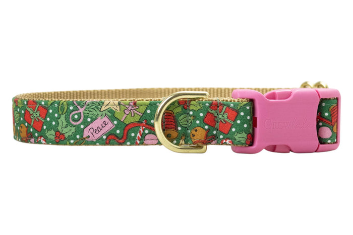 Festive Christmas dog collar in green with an all-over holiday print of gifts, holly, candy canes, bells, and ribbons, accented by snowy dots. Designed with a nylon woven backing, polished hardware, and engraved buckle.